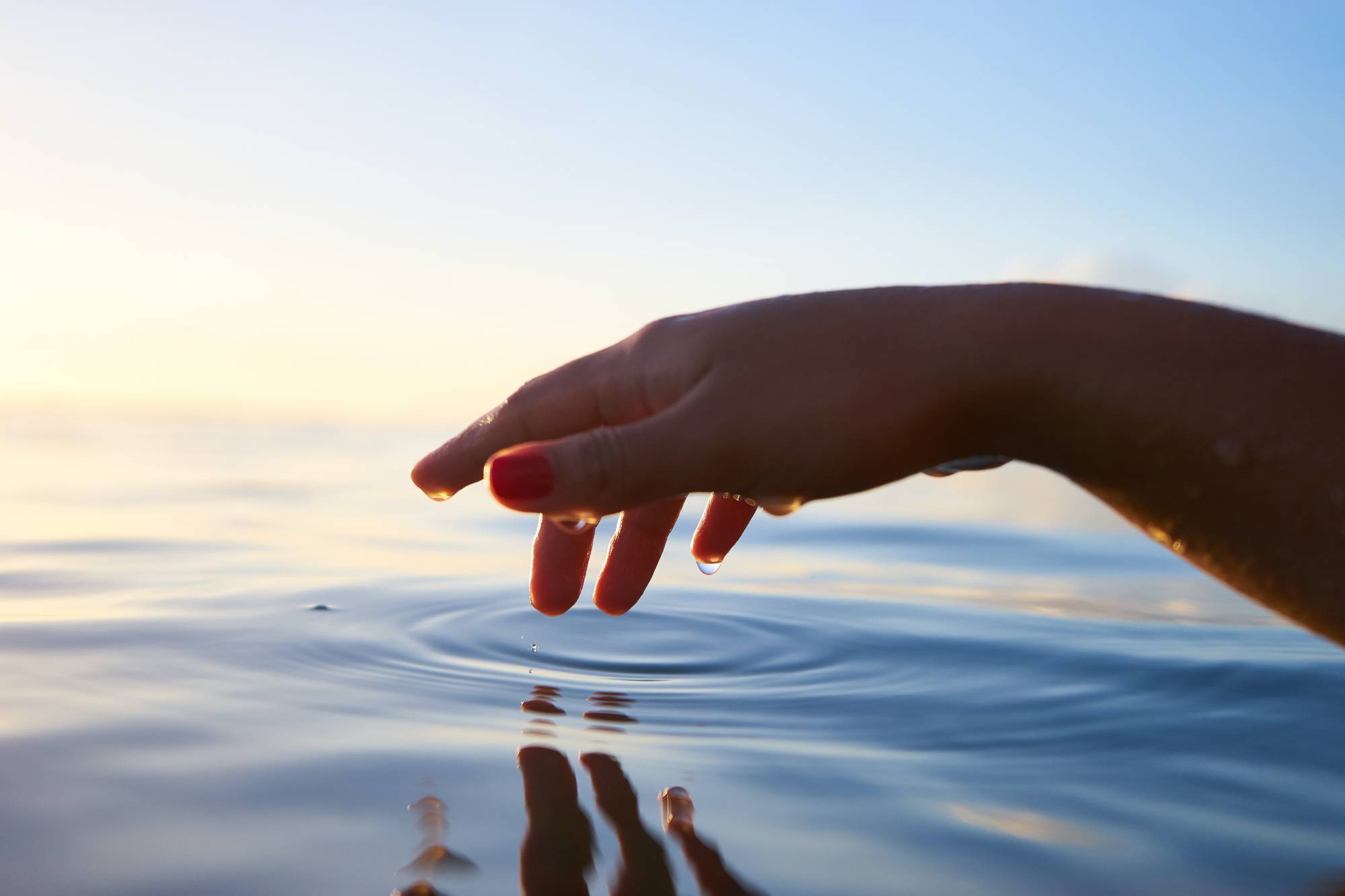 Hand touching the surface of the water. A comparison to pressing publish when writing online,